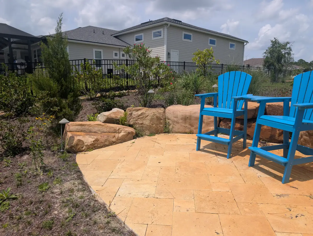Circular stone patio with blue chairs and a boulder border